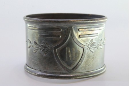 Argola de guardanapo em prata com motivos florais envolvendo cartela para monograma.